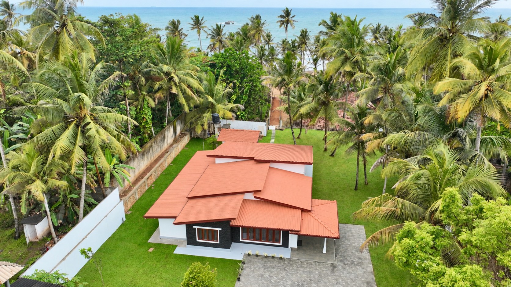 Aerial view of the villa's terracotta roof, palm garden and the sea beyond